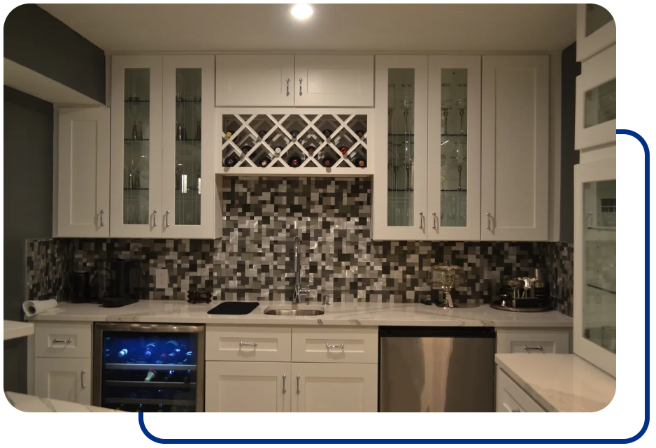 A kitchen with white cabinets and black tile backsplash.
