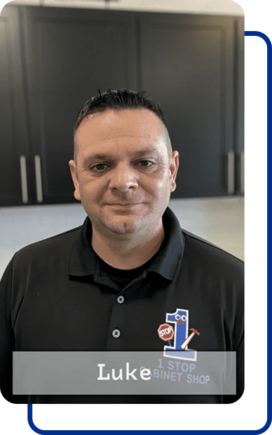 Man in black polo shirt, smiling indoors.